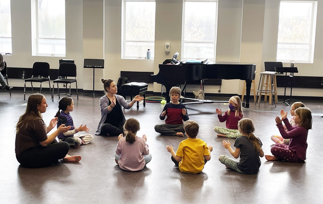 Young Kids Sitting in a Circle Clapping with Instructor During BW's Dalcroze Camp