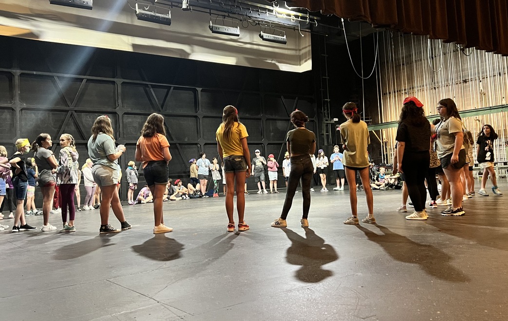 Group of Middle School Students Standing in a Circle Awaiting Direction from the Music Theatre Coach