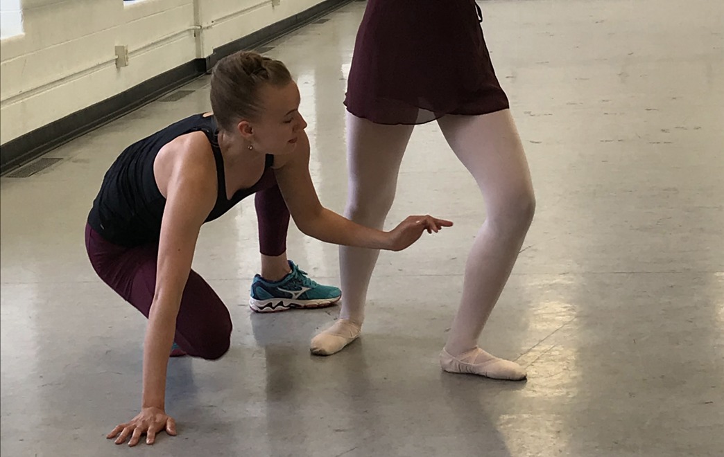 A BW Ballet Instructor Positioning a Student Dancer to Perfect Their Stance