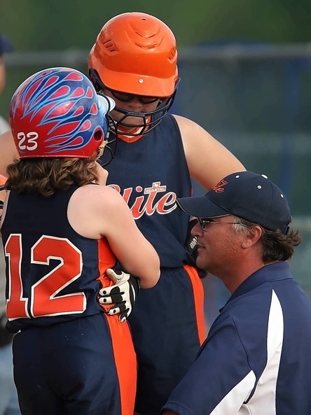 Softball Coach Guiding Two Players During a Game